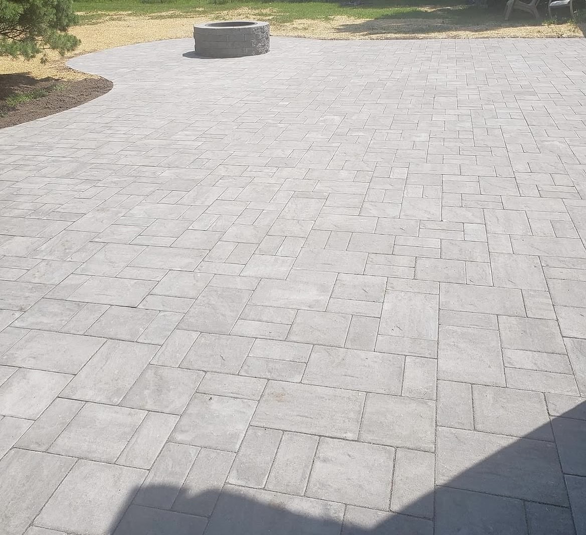 Large paver patio with a round stone fire pit