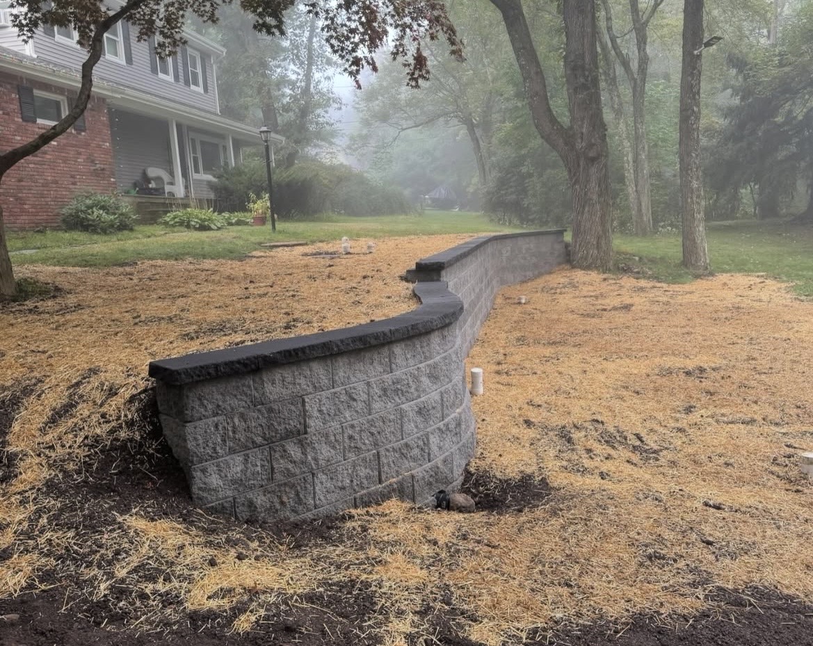 Curved block retaining wall with a charcoal cap
