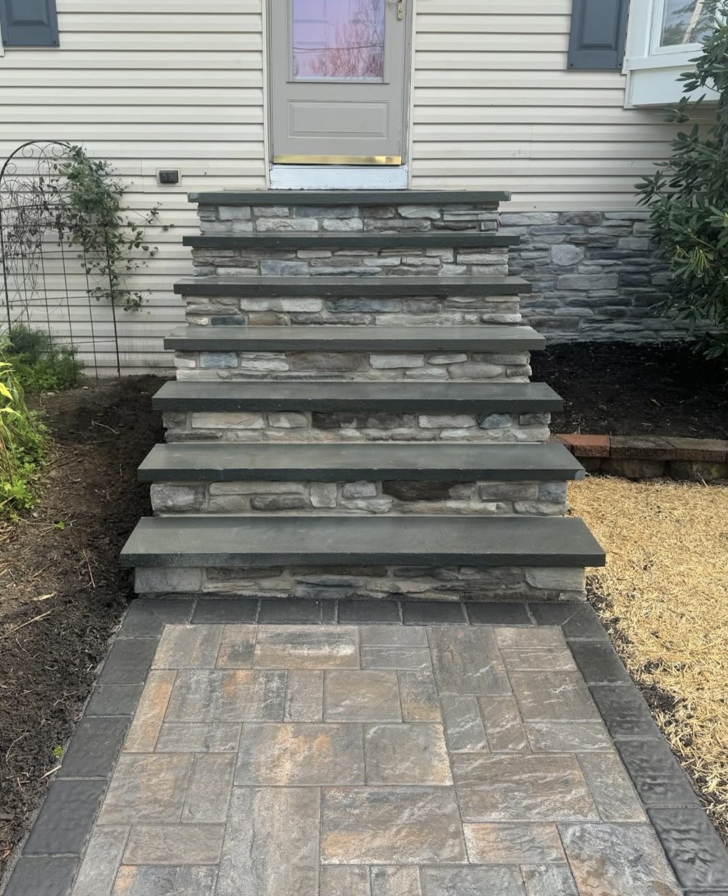 Stone-veneer front steps with bluestone treads and a paver landing