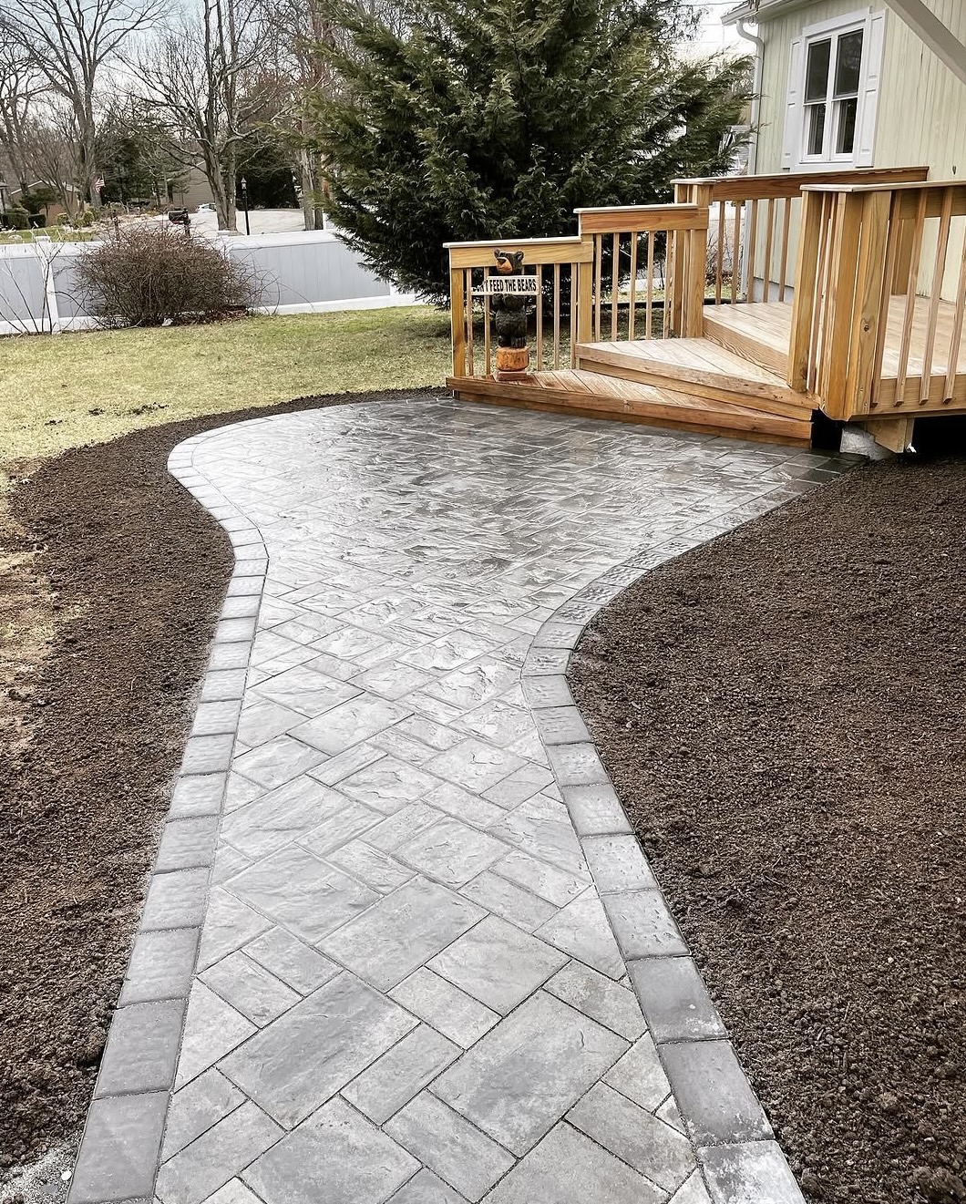 Paver walkway with planting beds leading to a wooden deck