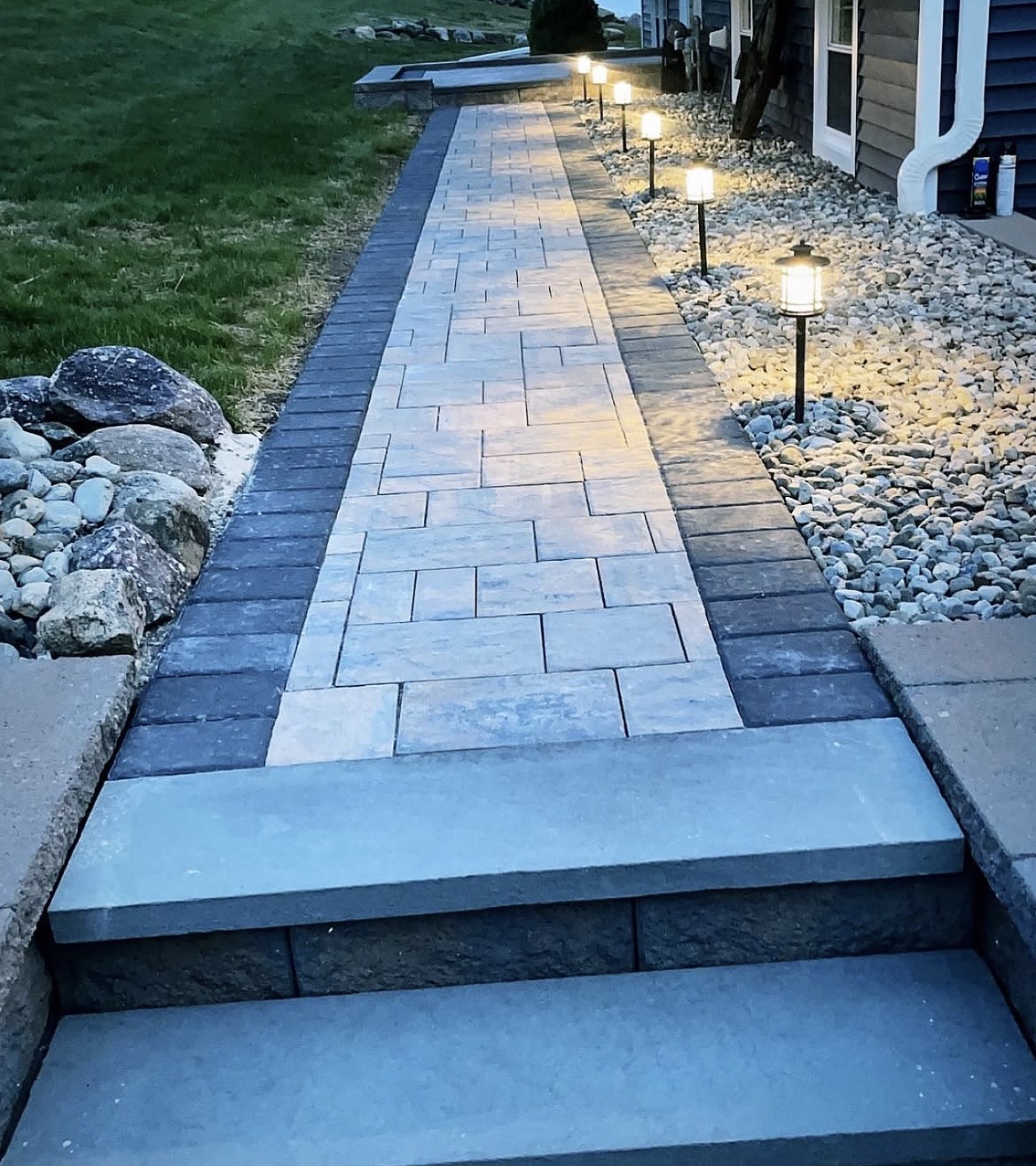 Paver walkway lit by landscape path lights at dusk